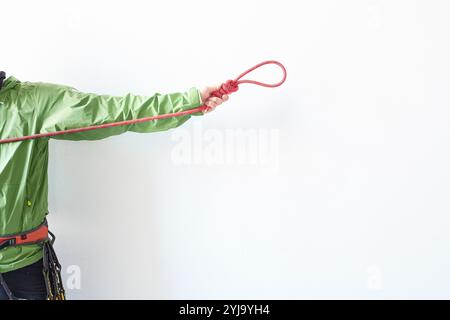 Grimpeur tenant et tirant une corde nouée devant un mur blanc Banque D'Images