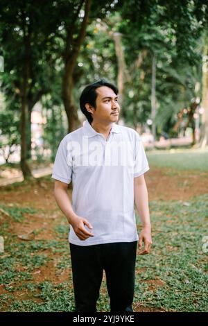 Homme d'Asie du Sud-est regardant vers la gauche, capturant un moment de concentration ou de curiosité. Idéal pour les projets liés à l'observation, à la contemplation ou aux decisi Banque D'Images
