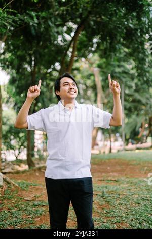 Homme d'Asie du Sud-est pointant vers quelque chose, capturant un moment de concentration ou d'instruction. Idéal pour les projets liés à la communication, à l'orientation ou à l'inter Banque D'Images