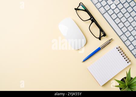Bureau avec clavier d'ordinateur, souris, lunettes, cahier et stylo. Vue de dessus avec espace de copie. Pose à plat Banque D'Images