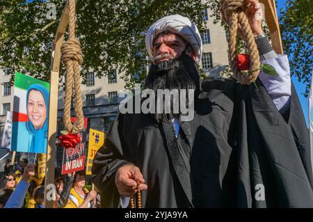 Londres, Royaume-Uni. 20 octobre 2018. Un homme habillé en ayatollah caresse le nœud sur un nœud coulant. Derrière une bannière "démocratie en Iran avec Maryam Rajavi", les moudjahidin du peuple iranien ont organisé une manifestation contre le régime répressif actuel en Iran, avec un gibbet et trois femmes détenues dans une cellule de prison illustrant le règne de la terreur là-bas et appelant à la fin des exécutions là-bas, des affiches nous ont rappelé que le régime iranien est le détenteur du record mondial des exécutions. Rajavi, le dirigeant de l'OMPI, a établi un manifeste en 10 points appelant à un système juridique moderne, l'égalité des sexes et politique et socia Banque D'Images