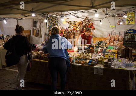 Bologne, Italie. 6 octobre 2024 - les visiteurs explorent un étal de marché du soir rempli de produits artisanaux Banque D'Images