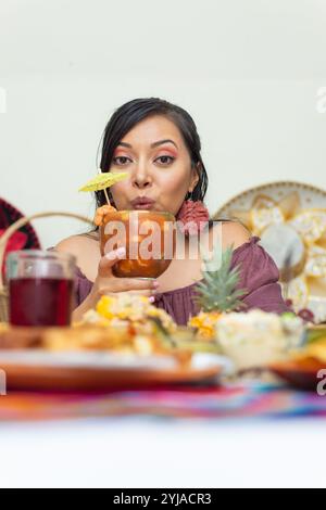 Femme tenant un verre de cocktail de crevettes entouré de plats de poisson. Banque D'Images