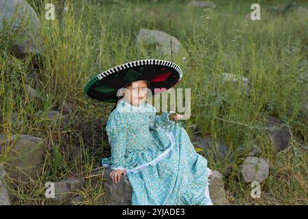 Petite fille portant un chapeau charro dans un paysage rural. Fête de l'indépendance mexicaine, célébration du cinco de Mayo. Banque D'Images