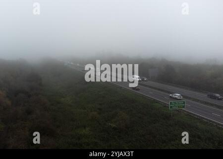 Cambridge, Royaume-Uni. 14 novembre 2024. Du brouillard est vu au-dessus de l'autoroute A14 à Cambridge. Selon le bureau DU MET, l'est de l'Angleterre va voir un début de journée nuageux avec une pluie légère inégale se dégageant vers le sud, devenant sèche avec des périodes ensoleillées se développant progressivement tout au long de la matinée. Crédit : David Tramontan / Alamy Live News Banque D'Images