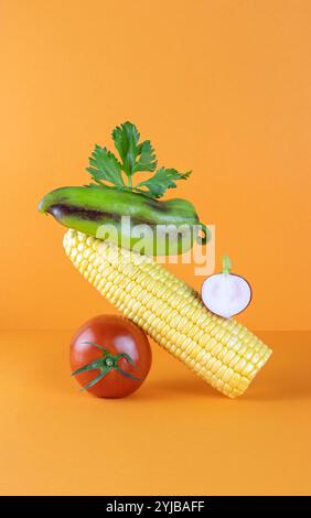 Équilibre des légumes sur la table. Flotteurs de légumes sur la table : tomate, poivron, maïs, radis sur fond orange. Banque D'Images