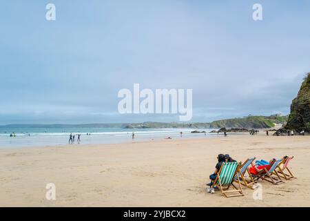 Visiteurs vacanciers visiteurs touristes assis dans des transats sur la plage de Towan à marée basse à Newquay en Cornouailles au Royaume-Uni. Banque D'Images