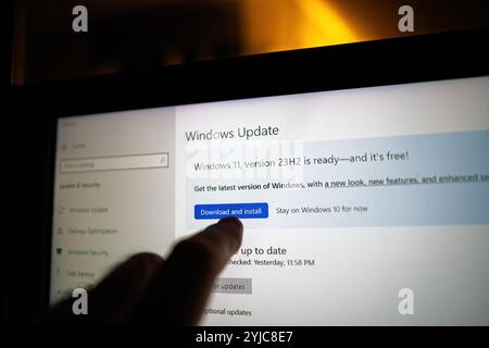 Paris, France - Sep 10, 2024 : pointage du doigt sur l'écran Windows Update sur un ordinateur portable, en mettant en évidence le bouton Télécharger et installer pour Windows 11 version 23H2, prêt pour la mise à niveau. Banque D'Images