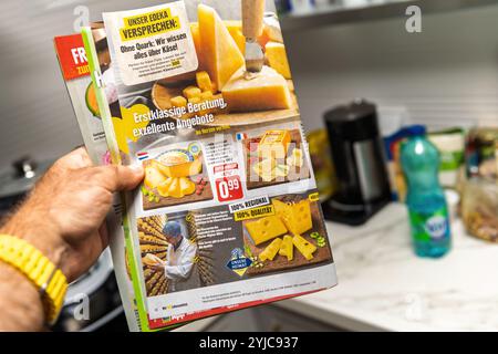 Francfort, Allemagne - 20 août 2024 : tient à la main un dépliant d'épicerie Edeka présentant divers fromages avec des allégations régionales et de qualité. Le dépliant met en évidence des offres spéciales sur les produits fromagers populaires Banque D'Images