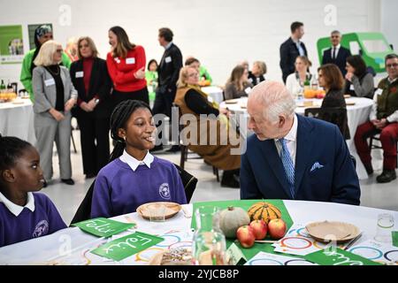 Le roi Charles III s’entretient avec des élèves de l’école primaire de Rye Oak alors qu’il visite le First Coronation Food Hub à Deptford, au sud de Londres. Le Roi célèbre son 76e anniversaire et le premier anniversaire du Coronation Food Project en ouvrant les deux premiers centres alimentaires Coronation, l’un en personne et l’autre virtuellement à Merseyside. Date de la photo : jeudi 14 novembre 2024. Banque D'Images