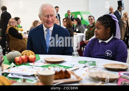 Le roi Charles III s’entretient avec des élèves de l’école primaire de Rye Oak alors qu’il visite le First Coronation Food Hub à Deptford, au sud de Londres. Le Roi célèbre son 76e anniversaire et le premier anniversaire du Coronation Food Project en ouvrant les deux premiers centres alimentaires Coronation, l’un en personne et l’autre virtuellement à Merseyside. Date de la photo : jeudi 14 novembre 2024. Banque D'Images