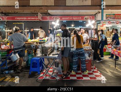 Bangkok, Thaïlande. 11 novembre 2024. Une vue de l'arrière d'un étal avec un vendeur de nourriture de rue qui grillent des bâtons sur un barbecue et des clients qui passent, au marché de Tao Poon, à Bangkok. Le marché de Tao Poon à Bangkok est un marché local connu pour sa cuisine de rue thaïlandaise authentique, ses produits frais et ses produits. C'est un endroit populaire pour les habitants et les touristes, et il est connu pour ses vendeurs amicaux et son atmosphère animée. Crédit : SOPA images Limited/Alamy Live News Banque D'Images