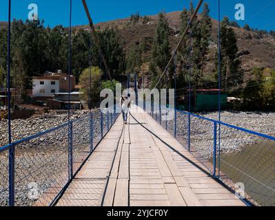 Huaraz, Ancash, Pérou - 22 juillet 2024 : un homme blanc traverse un pont suspendu qui enjambe la rivière Santa Ana Banque D'Images