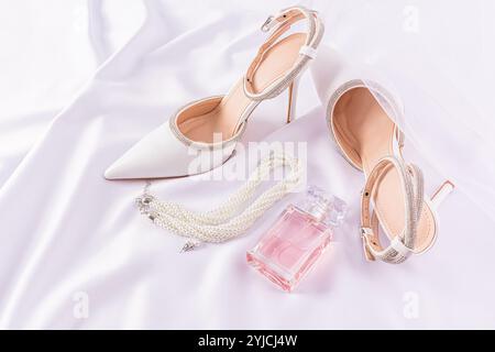 Belle vie morte de mariage du matin de la mariée. chaussures blanches avec strass, une bouteille de parfum rose, un collier de perles, un voile classique Banque D'Images