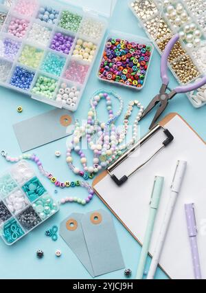 Kit de bricolage pour la fabrication de bracelets avec des perles colorées, pinces, presse-papiers, étiquettes de prix et autres outils sur la surface bleue avec espace de copie Banque D'Images