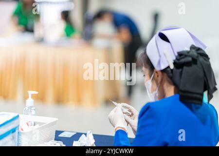 Nuse en bleu sui tester une syring sur la table. Banque D'Images