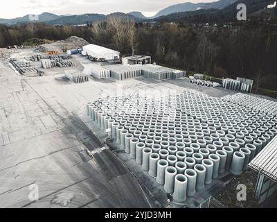 Les trous d'homme en béton de tuyau sont stockés sur le sol prêt pour la construction, pour drainer les eaux pluviales, fond industriel. Banque D'Images