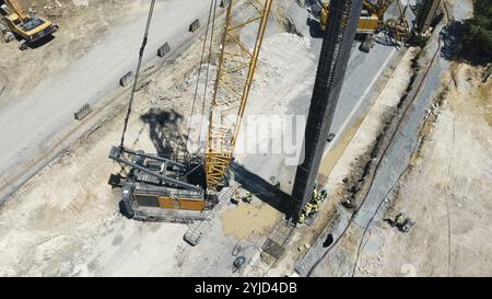 Grue levage barre d'armature avec ouvriers sur un chantier de construction vu d'en haut Banque D'Images