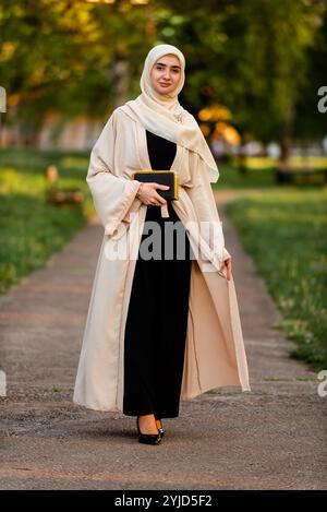 Portrait en longueur d'une belle femme musulmane portant un élégant hijab de mode moderne à l'extérieur. Banque D'Images