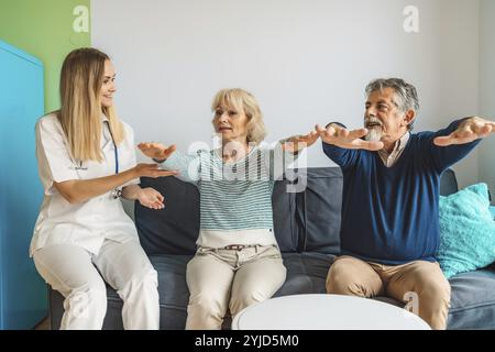 Jeune femme blonde aidante aidant un couple marié âgé à la maison. Infirmière accompagnant ses patients âgés en maison de retraite. Couple senior aidé par Banque D'Images