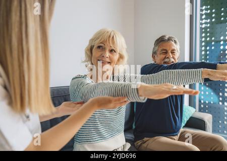 Jeune femme blonde aidante aidant un couple marié âgé à la maison. Infirmière accompagnant ses patients âgés en maison de retraite. Couple senior aidé par Banque D'Images