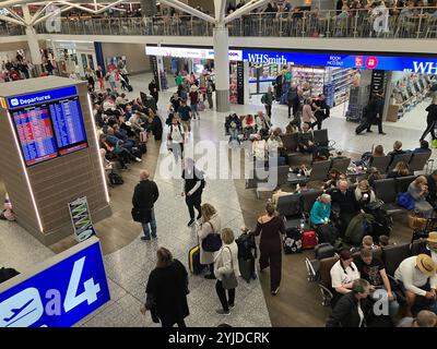 Salon de départ de l'aéroport bondé, du niveau supérieur regardant vers le bas avec des gens regardant les informations de porte sur le tableau attendant le vol Banque D'Images