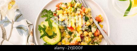 Une salade végétarienne vibrante composée de millet bouilli, de pois chiches, de légumes frais et d'avocat, arrosée d'huile d'olive pour un repas délicieux et sain Banque D'Images