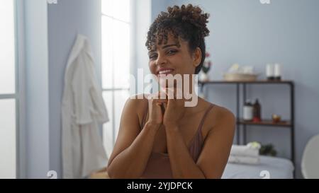 Belle jeune femme aux cheveux bouclés dans la salle de spa d'un centre de bien-être, profitant de l'ambiance relaxante Banque D'Images