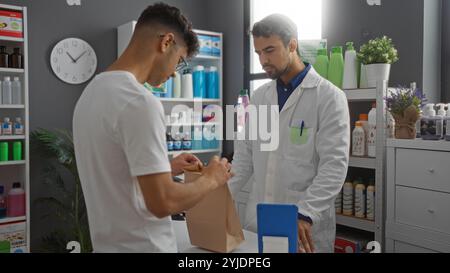 Pharmacien aidant le client masculin avec son achat dans une pharmacie bien approvisionnée, mettant en vedette divers produits médicaux et cosmétiques sur les étagères. Banque D'Images