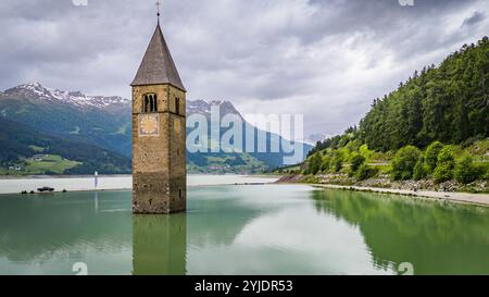 CURON VENOSTA, ITALIE – 27 AOÛT 2024 : le clocher emblématique de l’église submergée Curon Venosta s’élève des eaux du lac Resia, une Ré envoûtante Banque D'Images