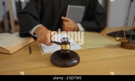 Juge frappant un marteau dans la salle d'audience avec un stylo à livre et une balance de justice sur le bureau pendant la procédure judiciaire Banque D'Images
