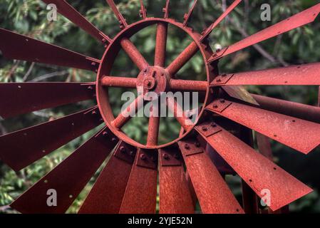 Moulin à vent fait maison peint en rouge utilisé comme décoration de cour. Un petit moulin à vent rouge brillamment peint est situé dans une cour avant Banque D'Images