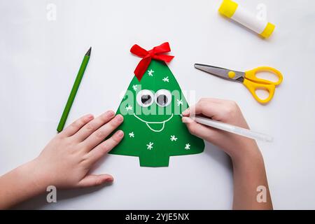 petit enfant faisant la décoration de noël à partir de papier. Projet artistique pour enfants. Arbre de Noël artisanal. Concept DIY. Instructions étape par étape pour la photo. Banque D'Images