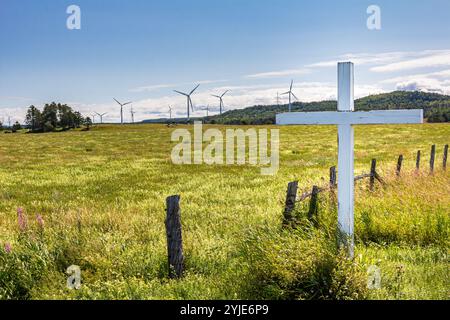 Croisement de bord de route dans un champ d'herbe et de fleurs sauvages, devant des éoliennes. Symbole religieux mélange avec la technologie. Banque D'Images