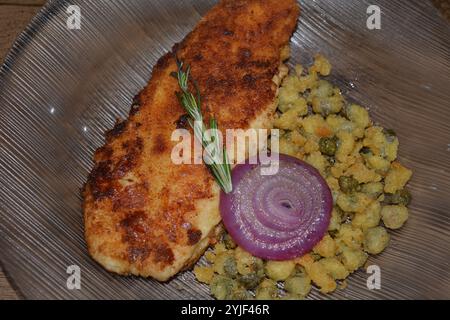 image d'un plat avec du poisson pané et des câpres panées, de l'oignon rouge et des brins de romarin Banque D'Images