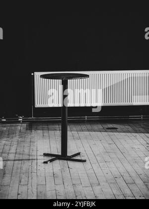 Intérieur monochrome avec table ronde noire sur plancher en bois Banque D'Images