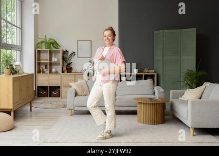 Jeune femme avec ordinateur portable moderne à la maison Banque D'Images