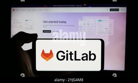 Allemagne. 9 août 2024. Dans cette illustration photo, une personne tient un téléphone portable avec le logo de la société américaine de logiciels open-source GitLab Inc en face de la page Web de l'entreprise. (Crédit image : © timon Schneider/SOPA images via ZUMA Press Wire) USAGE ÉDITORIAL SEULEMENT ! Non destiné à UN USAGE commercial ! Banque D'Images
