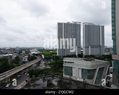 Vue aérienne du paysage urbain de Jakarta, mettant en valeur des appartements imposants de grande hauteur le long d'une gare animée, architecture moderne contre un d Banque D'Images