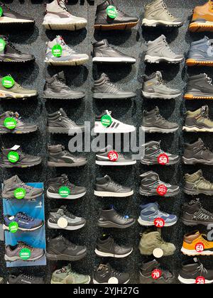 Kiev, Ukraine - 14 novembre 2024 : une gamme variée de baskets et de bottes présentées sur un mur de magasin, mettant en vedette plusieurs marques et styles avec un prix ta Banque D'Images