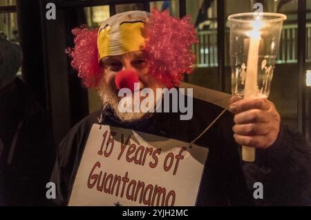 Londres, Royaume-Uni. 11 janvier 2018. Un manifestant porte un masque de clown et une pancarte "16 ans de Guantanamo, c'est pas de rire" lors de la veillée aux chandelles que l'ambassade américaine a célébrée le 16e anniversaire du camp de torture illégal de Guantanamo Bay où 41 prisonniers sont toujours détenus, principalement indéfiniment sans inculpation ni procès et la plupart avec des blessures permanentes causées par la torture qui rendraient leur libération embarrassante pour les autorités américaines (et peut-être britanniques). Les manifestants ont allumé des bougies devant la clôture de l'ambassade en écrivant « GITMO », puis se sont tenus debout avec des bougies et de grandes photographies du 41 Banque D'Images