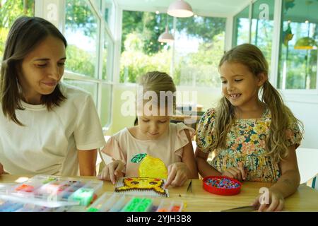 Professeur dans l'atelier a techno deux filles comment assembler une mosaïque thermo Banque D'Images