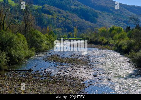 Une vue pittoresque sur la rivière Saja qui coule à travers la vallée de Cabuerniga en Cantabrie, Espagne. Les eaux claires de la rivière reflètent la lumière du soleil. Banque D'Images