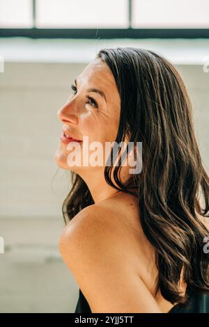 Femme regardant vers le haut avec un doux sourire, capturé dans la lumière naturelle Banque D'Images