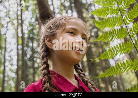 Petite fille marchant dans la forêt le jour de sunne admirant la nature Banque D'Images