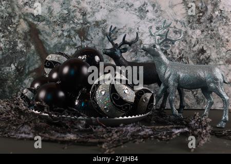 Figurines de cerfs métalliques et bleues entourées de décorations de Noël noires et argentées Banque D'Images