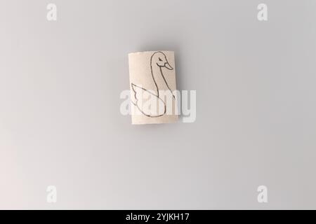 Comment faire un oiseau de cygne à partir de rouleaux de papier toilette, art de processus, jouet miniature, étape dans le processus créatif, bricolage, vue de haut en bas, fond gris Banque D'Images