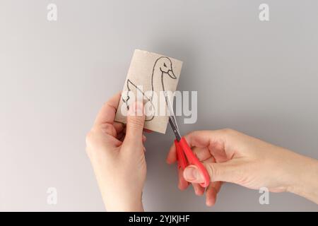 Tutoriel comment découper le jouet d'oiseau cygne en papier, recycler l'art, concept d'artisanat de rouleau de papier toilette pour enfant et maternelle, bricolage, vue de haut en bas des mains avec s. Banque D'Images