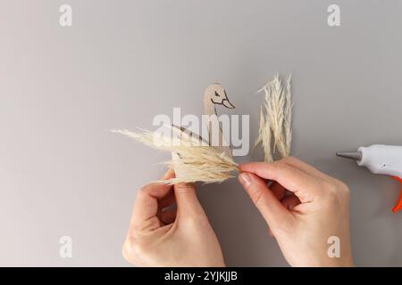 idées utiles pour la classe recyclant le papier et les matériaux naturels comme l'herbe sèche, l'occupation des enfants de temps de jeu, vue de haut en bas des mains de femme faisant l'oiseau cygne Banque D'Images
