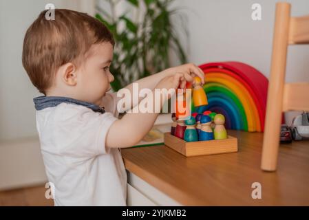 Un enfant Montessori garçon d'apprentissage ludique arrangeant par engagé en bois coloré blocs sensoriels éducatifs jouets cognitifs compétences créatives. Banque D'Images